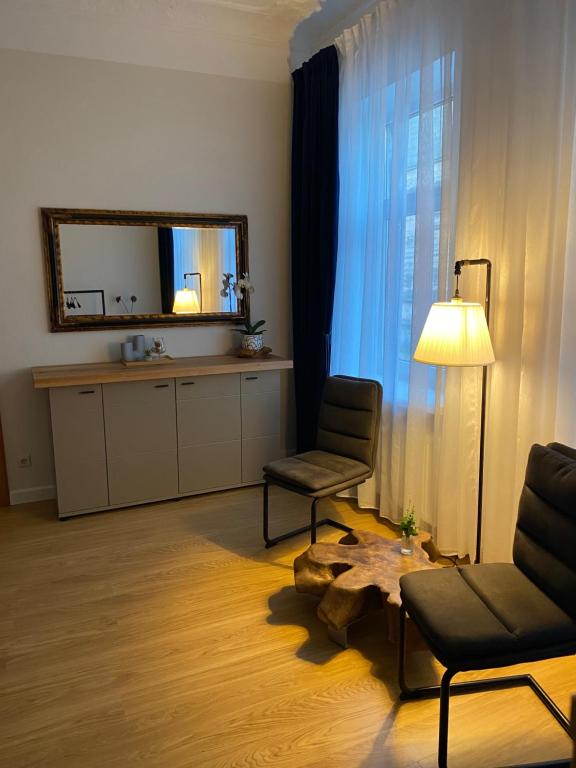 a living room with a chair and a table and a mirror at Zviedru Nams in Liepāja