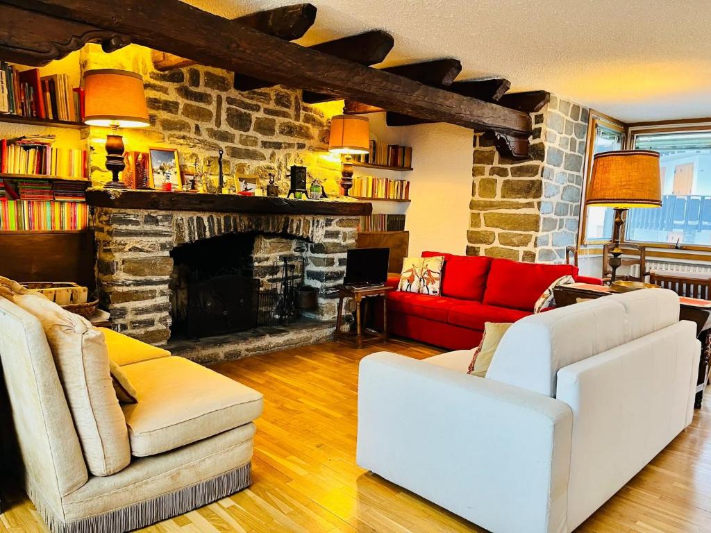 a living room with two white chairs and a stone fireplace at GuestHost - Il Dente del Gigante in Courmayeur