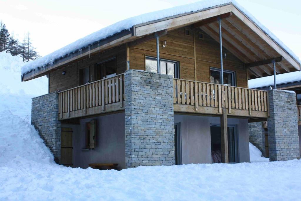 a log cabin with a balcony in the snow at Normalie in Villarodin-Bourget