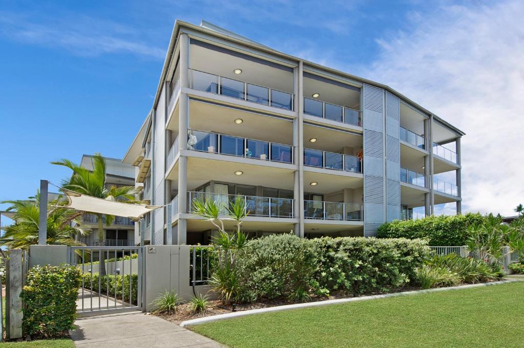 un immeuble d'appartements avec des buissons devant lui dans l'établissement On the Bay Apartments, à Bongaree