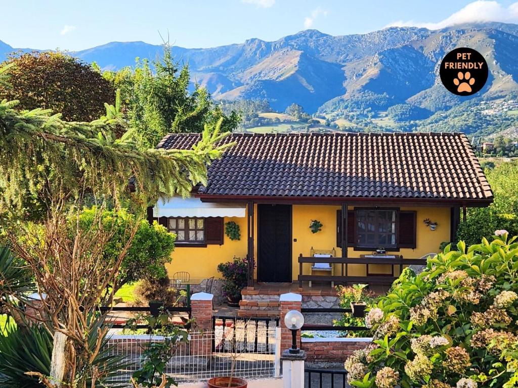 a yellow house with mountains in the background at Rincón de Madagascar VV-2192-AS in Arriondas