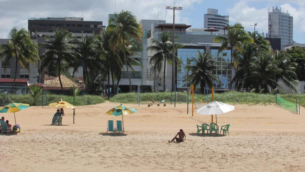 a group of people sitting on a beach with umbrellas at Praiano Flat Tambaú in João Pessoa