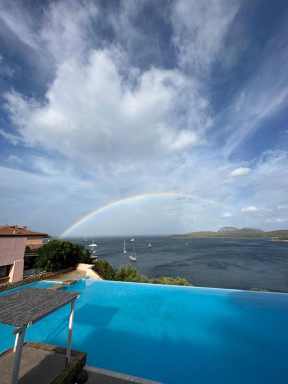 a rainbow over a swimming pool with a view of the water at Studio flat in Sardinia Costa Smeralda in Porto Rotondo