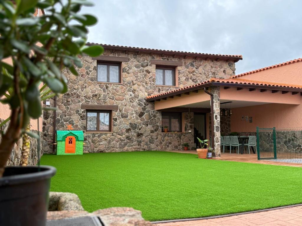 a house with a green lawn in front of it at Casa Rural Tomillo in Navalcán