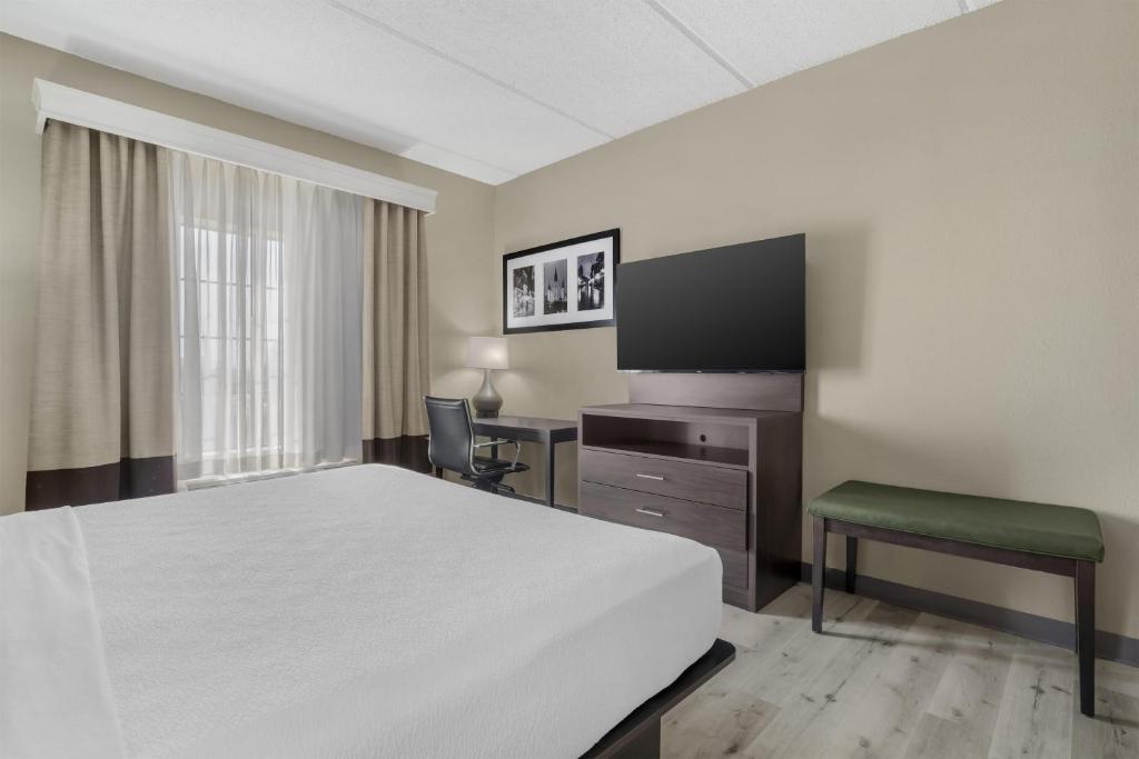 a hotel room with a bed and a desk and a television at Best Western Kenner in Kenner