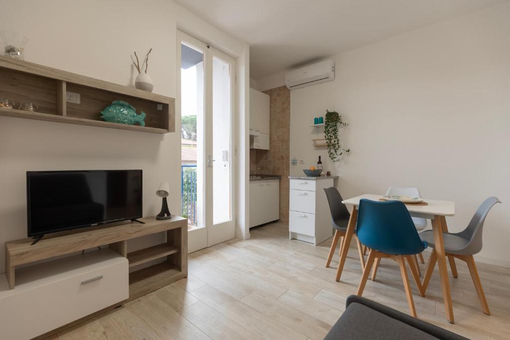 a living room with a television and a table with chairs at Appartamento Tre Api by ElbaSummer in Procchio