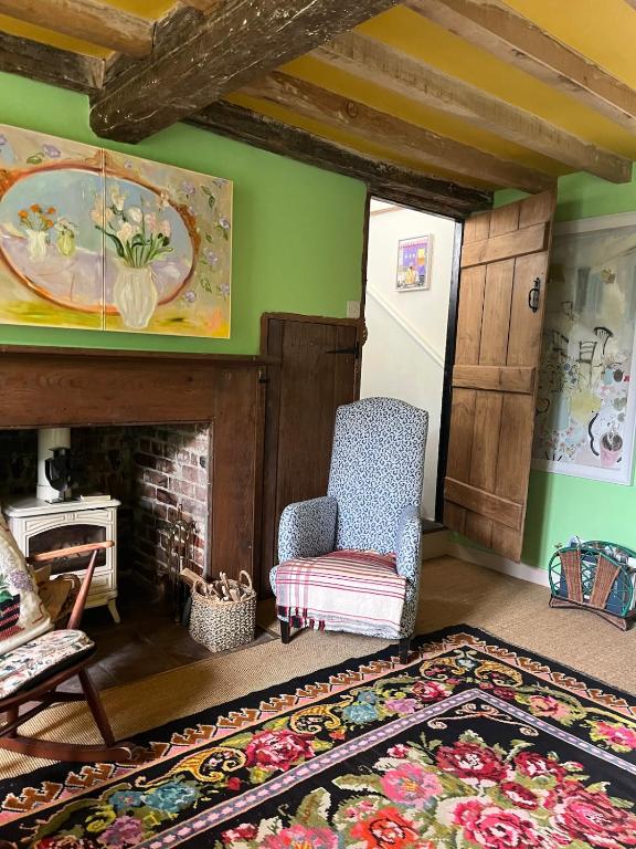 a living room with a chair and a fireplace at Cuckoo Bush Cottage - A unique cottage retreat in Holt