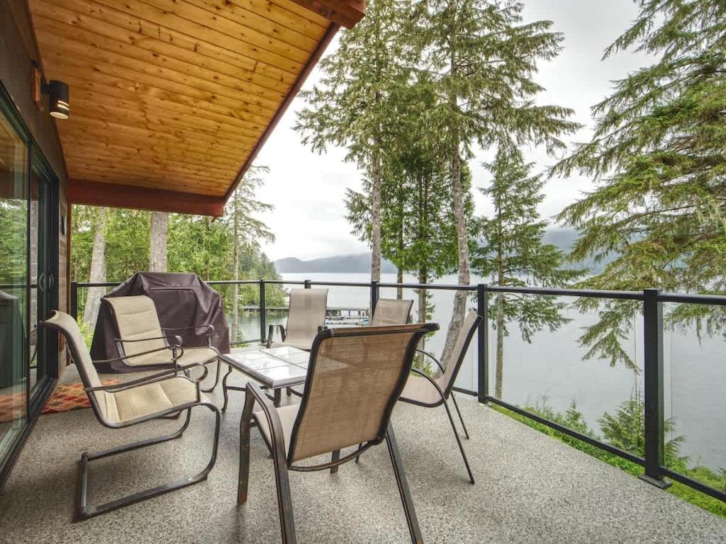 a patio with chairs and a table and a view of the water at Going Coastal A - Oceanfront - Pet Friendly in Port Renfrew