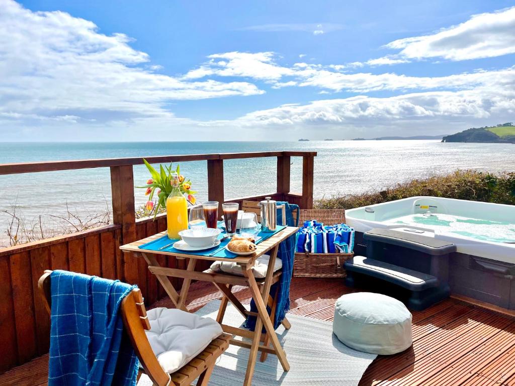 a deck with a table and a bath tub at Crows Nest Dawlish in Dawlish