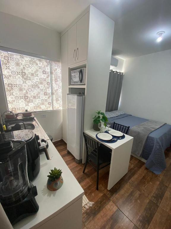 a small room with a bed and a table and a kitchen at KIT 300- com Ar cond - 5 min do aeroporto, rodoviária e embaixadas in Brasília