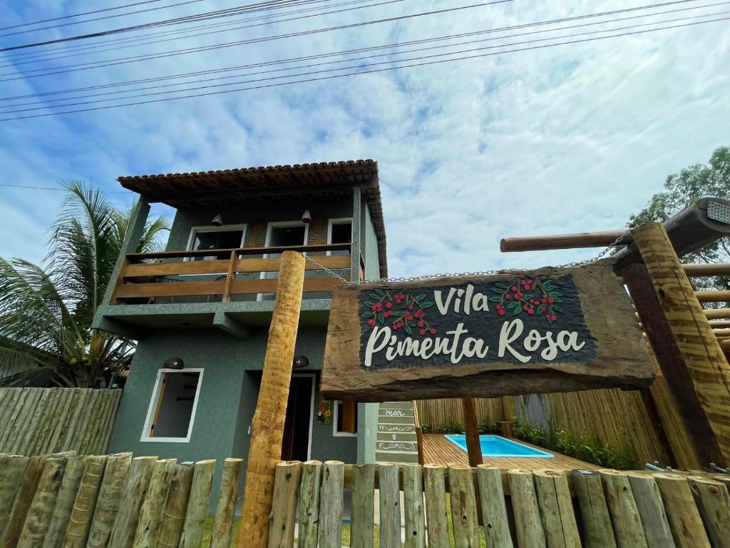 a house with a sign in front of a fence at Vila Pimenta Rosa in Caraíva