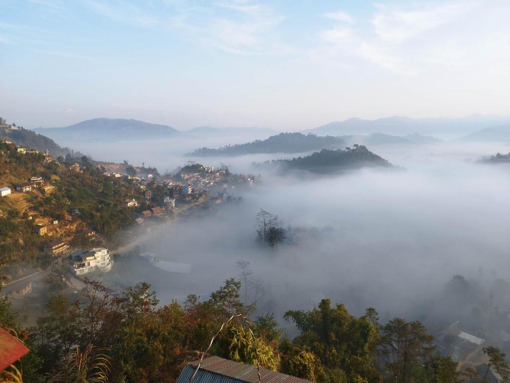 a view of a fog covered valley with a city at Balthali himalaya view point restro in Panaoti