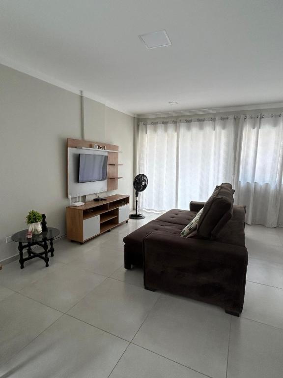 a living room with a couch and a flat screen tv at CASA ESPAÇOSA e CONFORTÁVEL EM PARATY in Paraty