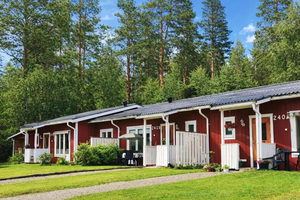 a row of red cottages with trees in the background at Jojos Lodge in Bräcke