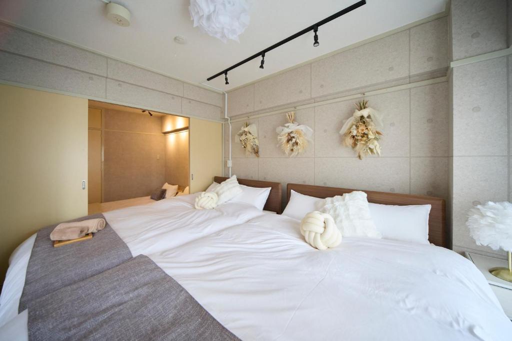 a bedroom with a large white bed with white pillows at Mezon Etowaaru in Nagoya
