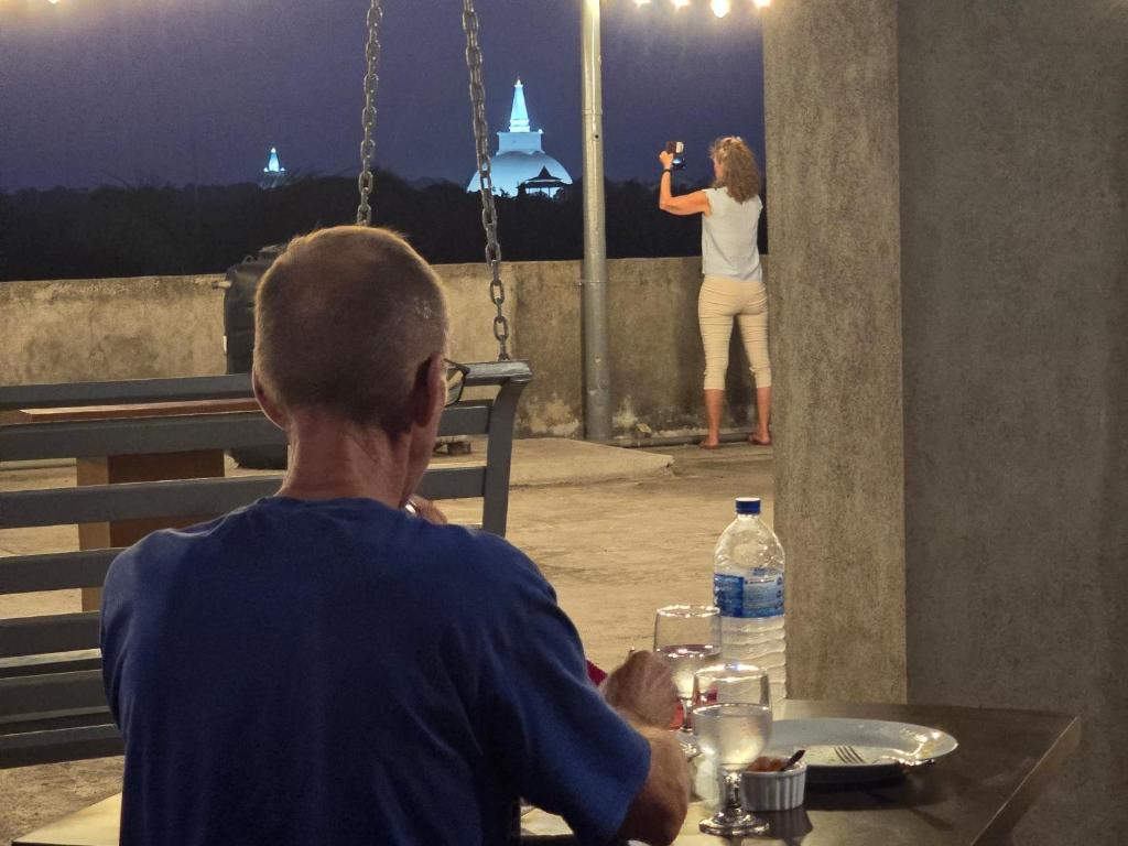 un uomo seduto a un tavolo che guarda una donna di CTC Receptions a Anuradhapura