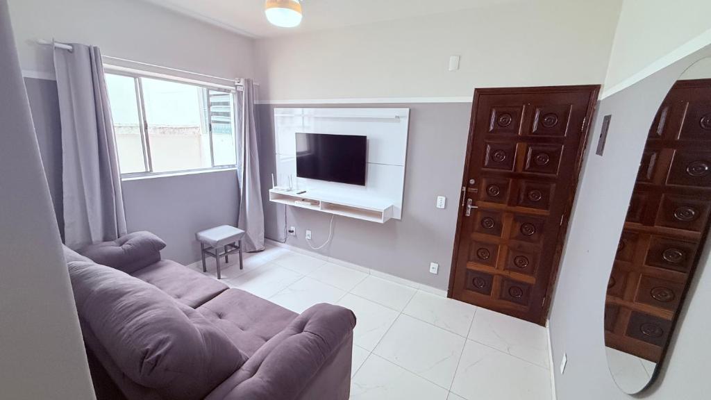 a living room with a couch and a television at Achadinho no Coração de Aparecida 2 in Aparecida