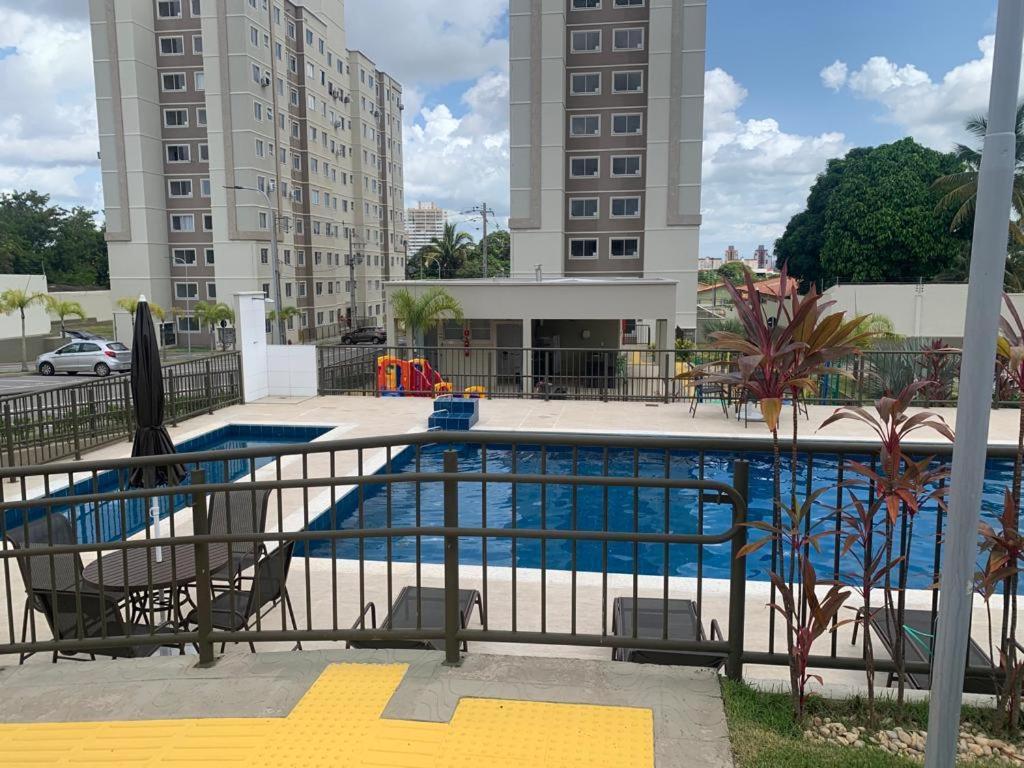 a swimming pool with two chairs and two tall buildings at MaM TORRE DOS HOLANDESES in São Luís