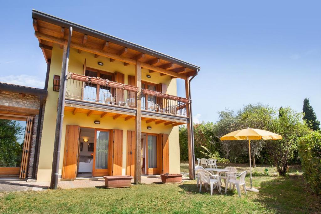 a house with a balcony and a table and an umbrella at Casa Flora in Garda