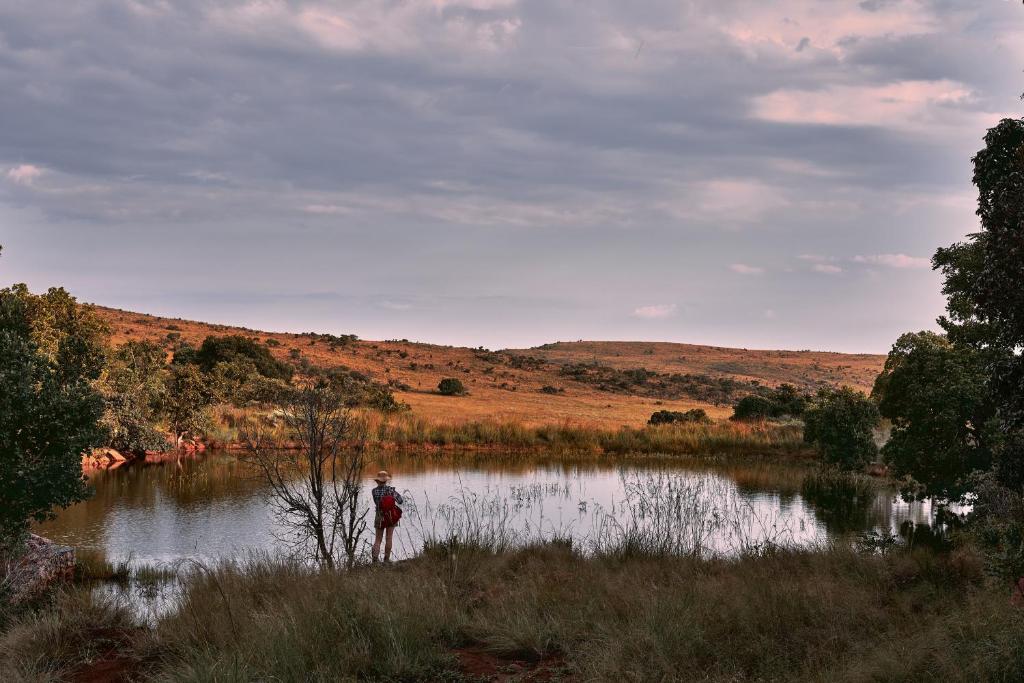 a person standing in front of a lake at Bateleur Nature Reserve & Stamvrug Hiking Trails in Modimolle