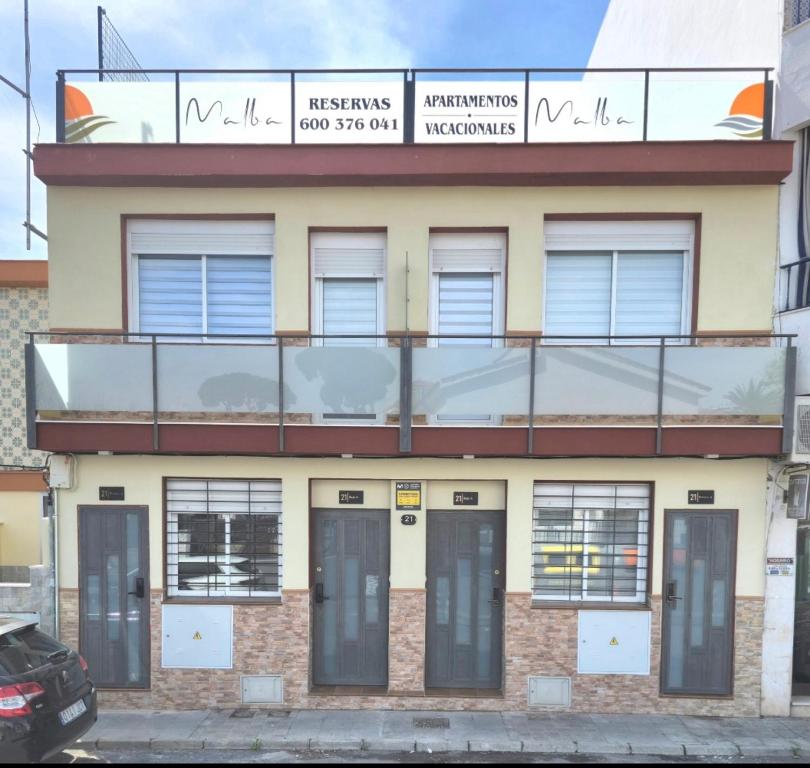 a building with windows and doors on a street at Apartamentos Vacacionales Malba Primero A in Punta Umbría