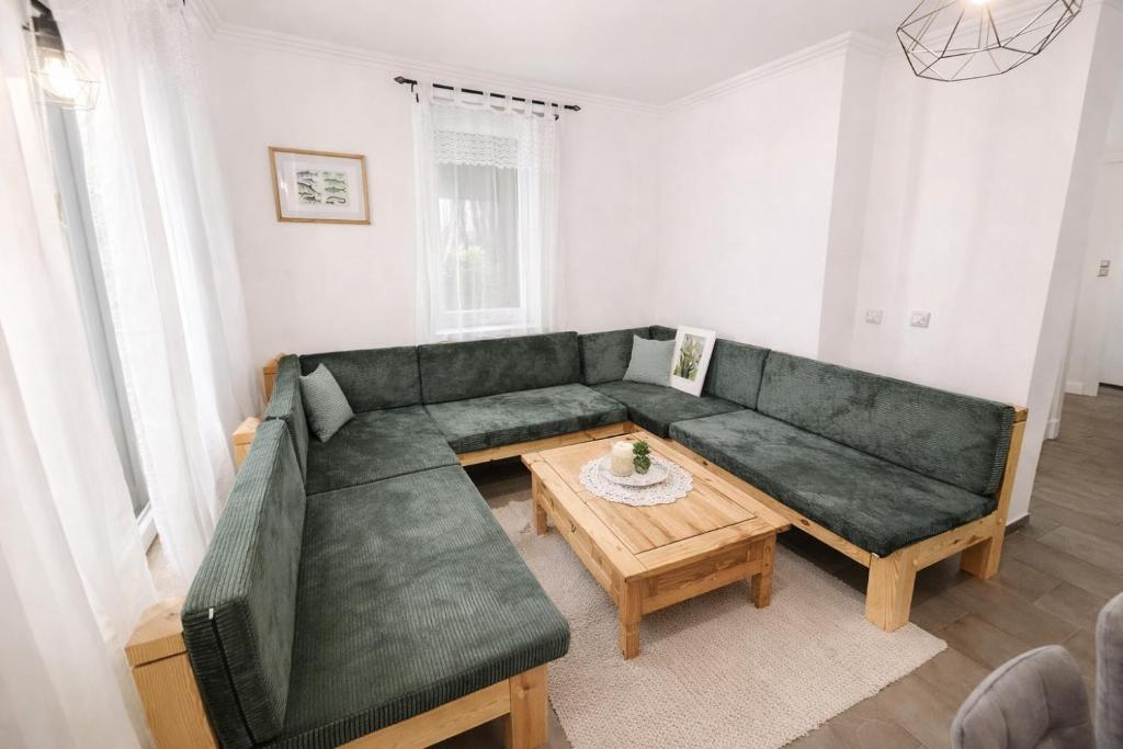 a living room with a green couch and a table at Spreewald Błota Jéwa Ferienwohnung mit Terrasse und Parkplatz in Lübbenau