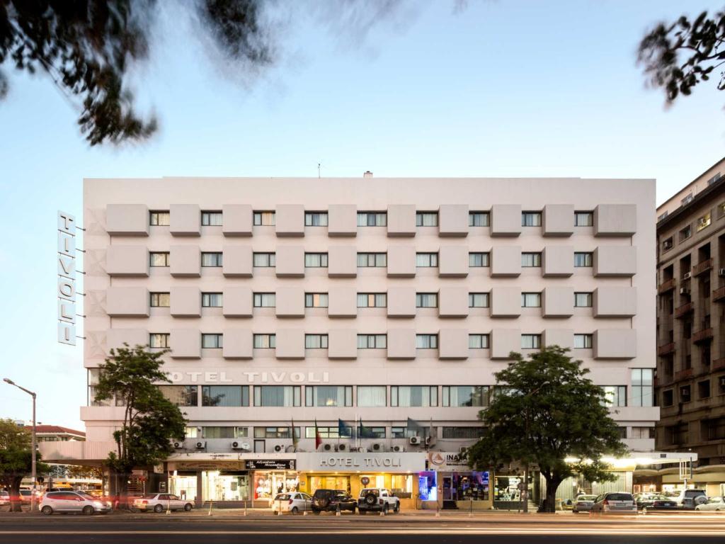 a large white building with windows on a city street at Hotel Tivoli Maputo in Maputo