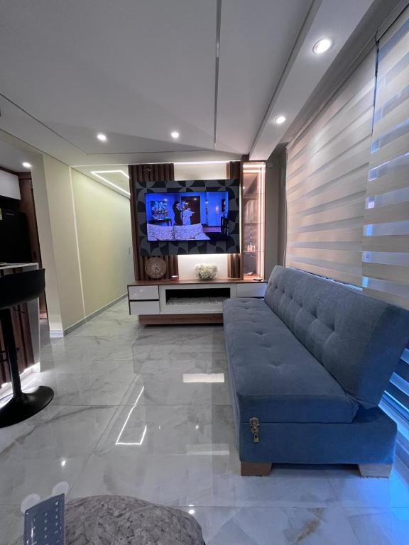a living room with a blue couch and a flat screen tv at El lujo y la comodidad in Zipaquirá