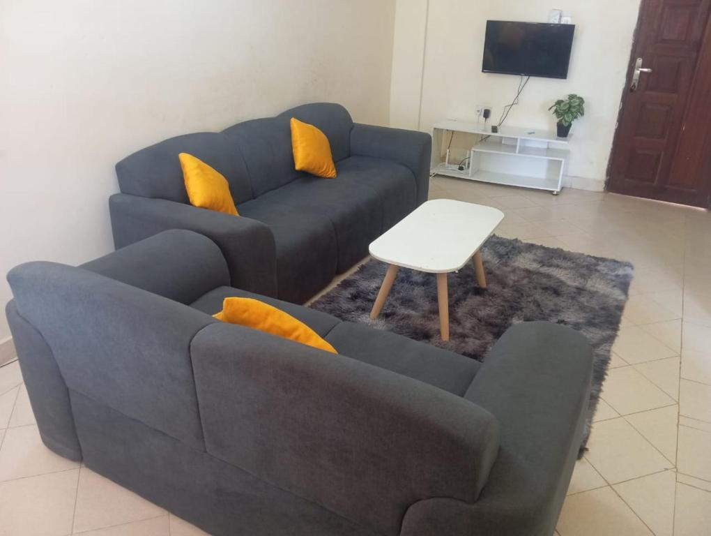 a living room with a blue couch and yellow pillows at Nest Apartment Diani in Diani Beach