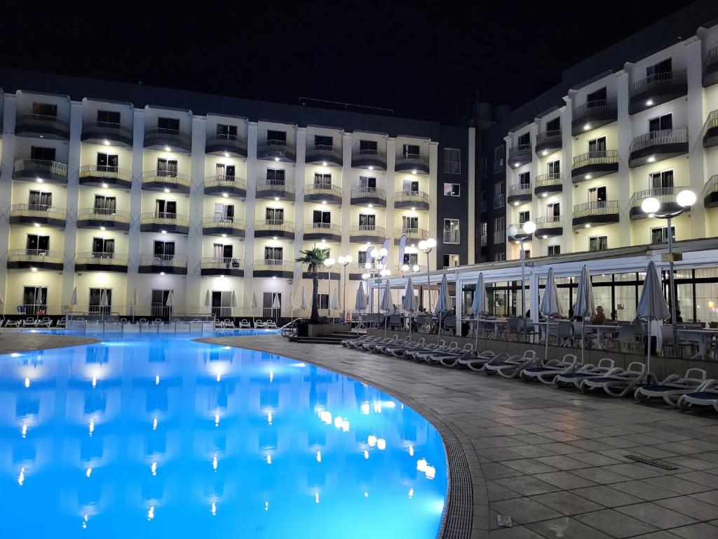 un hotel con una piscina blu di fronte a un edificio di Topaz Hotel a San Pawl il-Baħar
