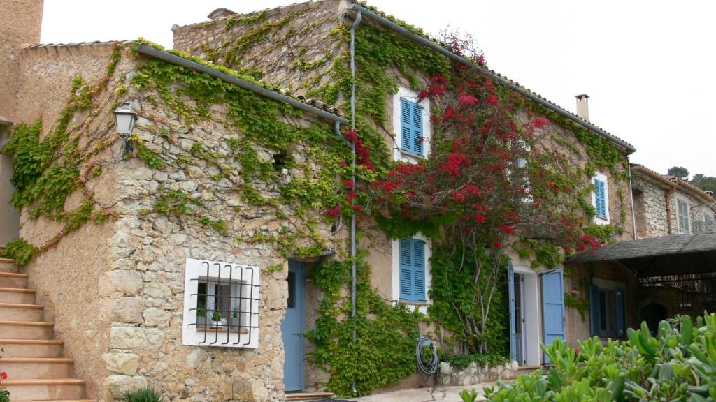 un edificio de piedra con flores rojas. en Son Reus, en Es Carritxo