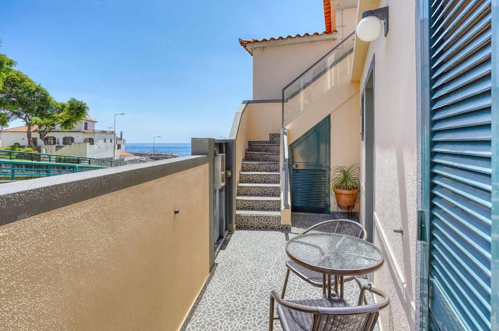 a balcony with two chairs and a table and some stairs at Vilamar 2 - Madeira Inn Group in Calheta