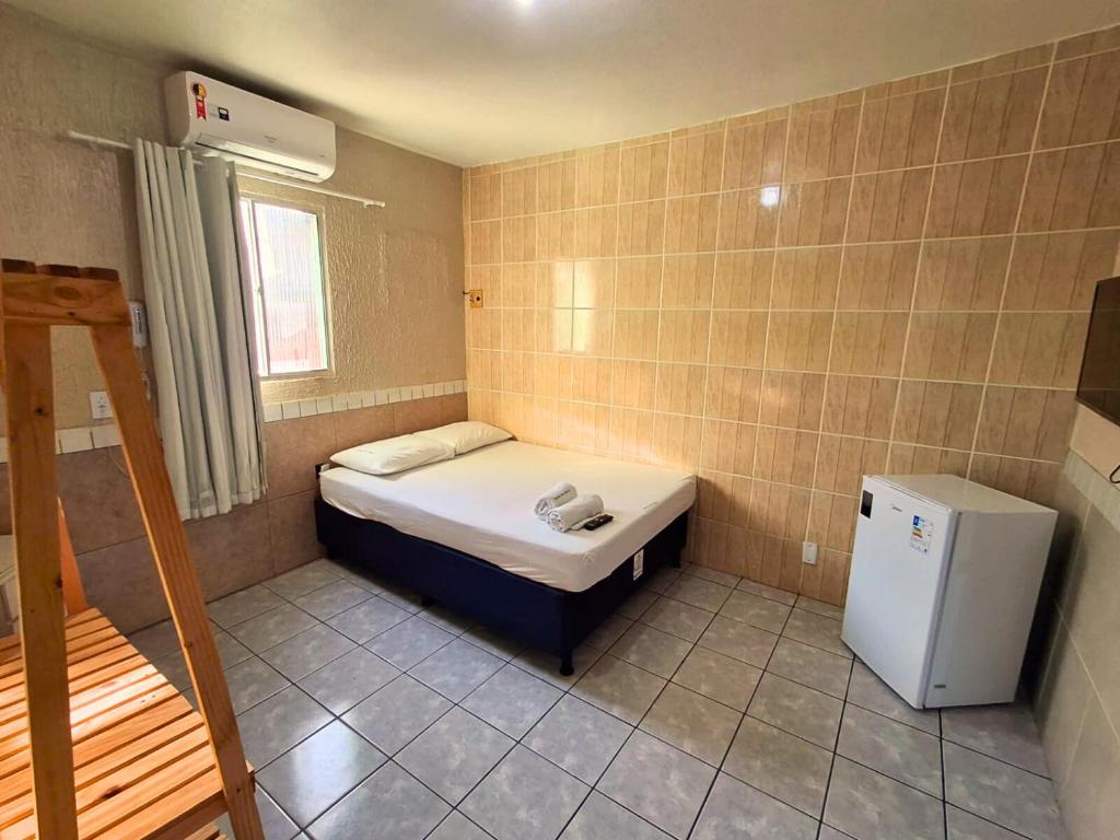 a small room with a small bed and a refrigerator at Pousada Dom Manuel - Ce in Fortaleza