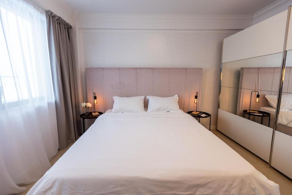 a bedroom with a large white bed with two lamps at White Residence Steaua De Mare in Eforie Nord