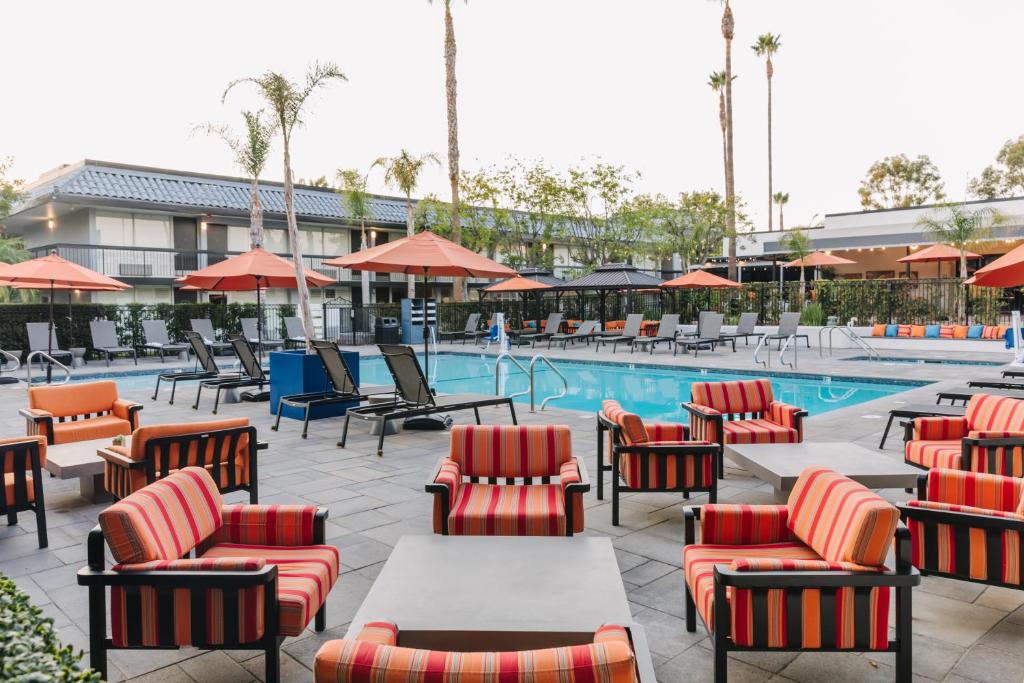 a patio with chairs and tables and a swimming pool at Palm Garden Hotel in Thousand Oaks