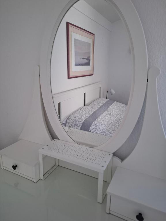 a white bedroom with a bed and a mirror at RETRO Apartments in Bjelovar