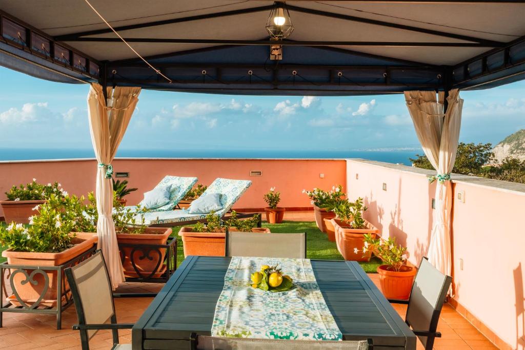 a patio with a table and chairs and the ocean at Sunset Terrace Sorrento Coast in Sant'Agnello