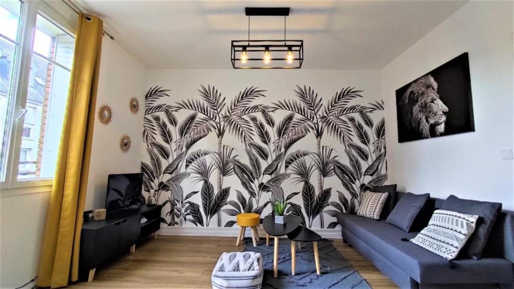 a living room with a blue couch and palm trees mural at Le Petit Jacobin - City center in Beauvais