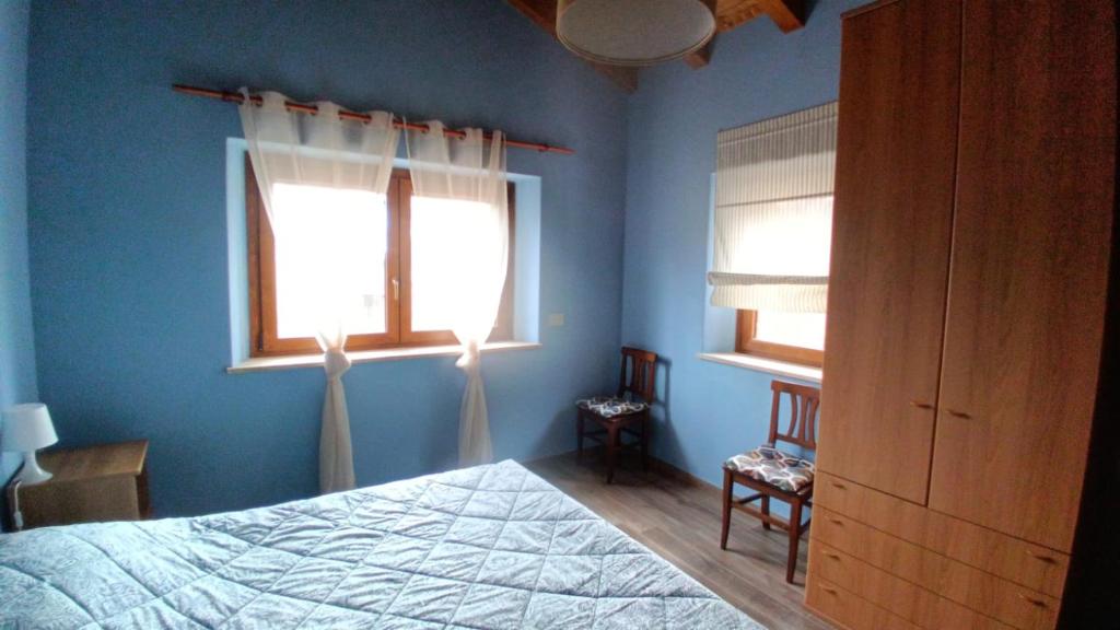 a blue bedroom with a bed and two windows at Ospitalità Adocentyn in Guinadi