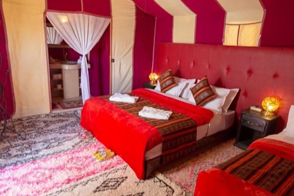 a bedroom with a bed with a red head board at Merzouga Dream Camp in Merzouga