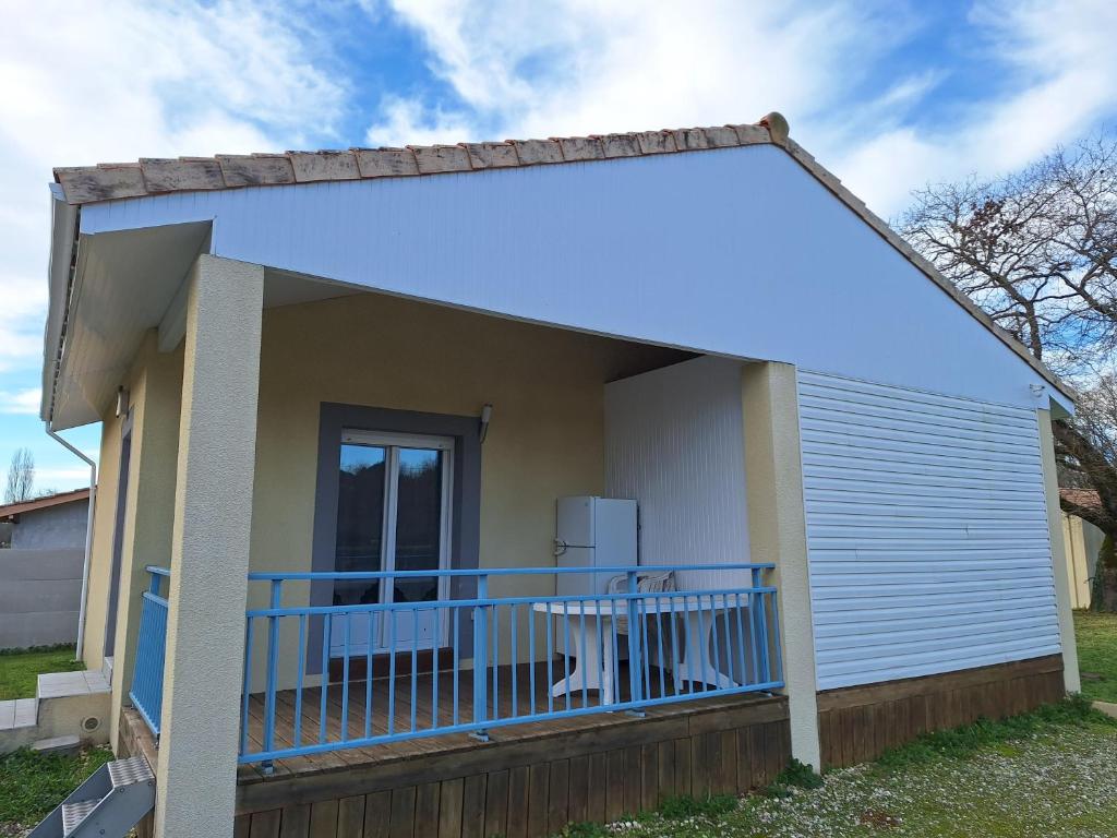 a house with a large front porch with a blue railing at Petite maison calme in Queyrac