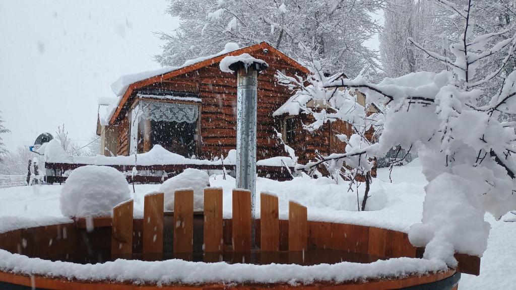 a log cabin in the snow with a fence at Cabaña Rakin Guilliw in Lonquimay