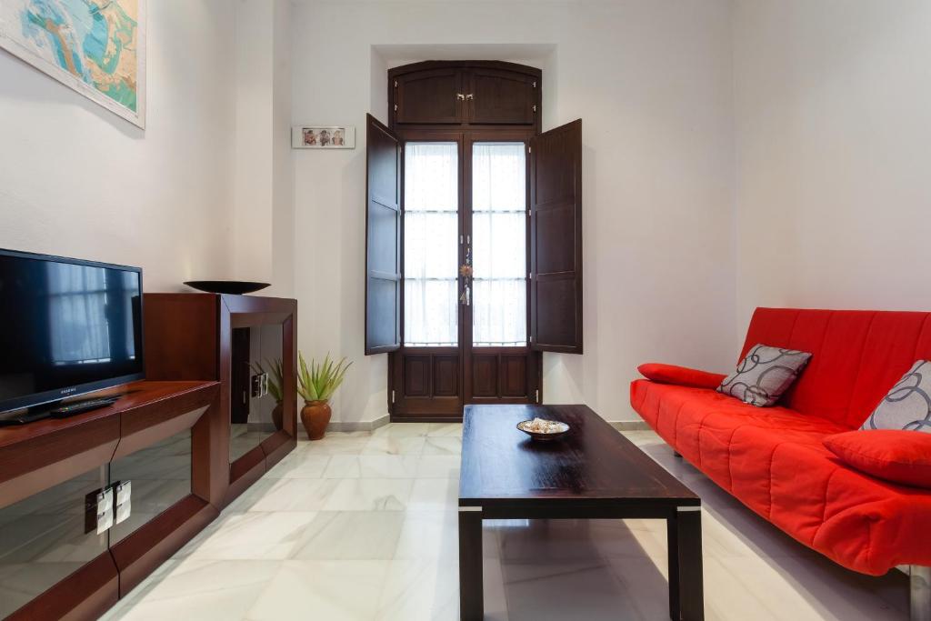 ein Wohnzimmer mit einem roten Sofa und einem TV in der Unterkunft Casa ALEGRIA by Cadiz4Rentals in Cádiz