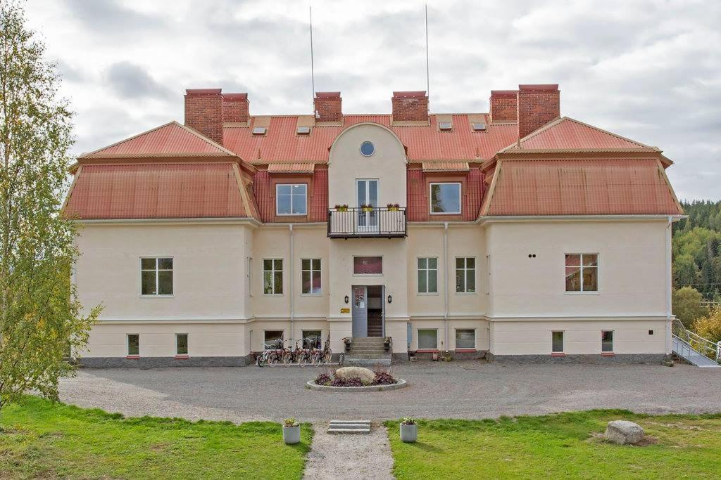 un grand bâtiment blanc avec un toit rouge dans l'établissement Norrfly Herrgård, à Kilafors