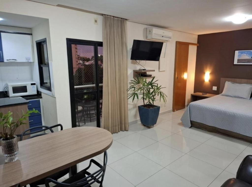 a hotel room with a bed and a table and a dining room at Crystal Place Flat 509 in Goiânia