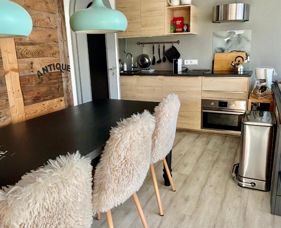 a kitchen with a black table and white chairs at Poppenberg Lodge in Winterberg
