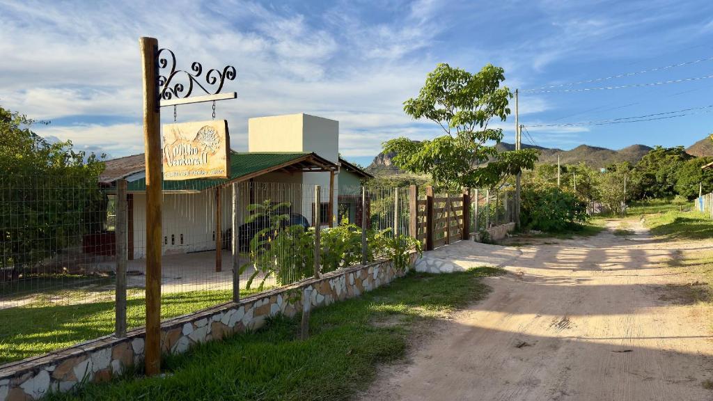 a building with a sign next to a dirt road at Milho Ventura II, Vila Pôr do Sol in Sêrro