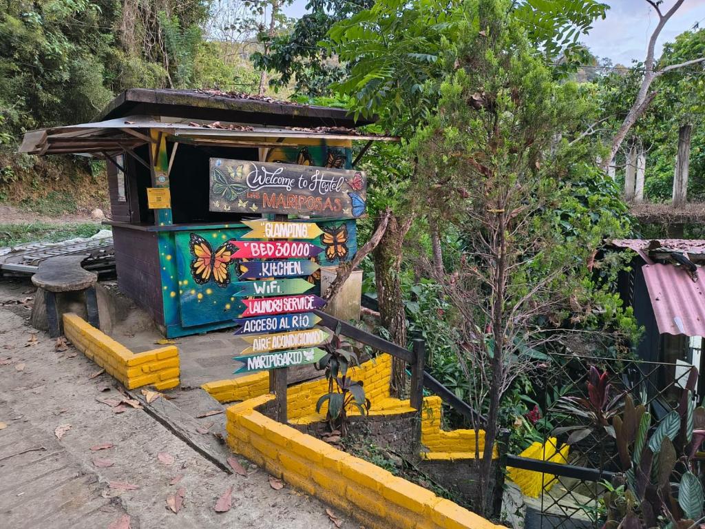 a directional sign in front of a building with trees at Hostal Las Mariposas Minca in Minca