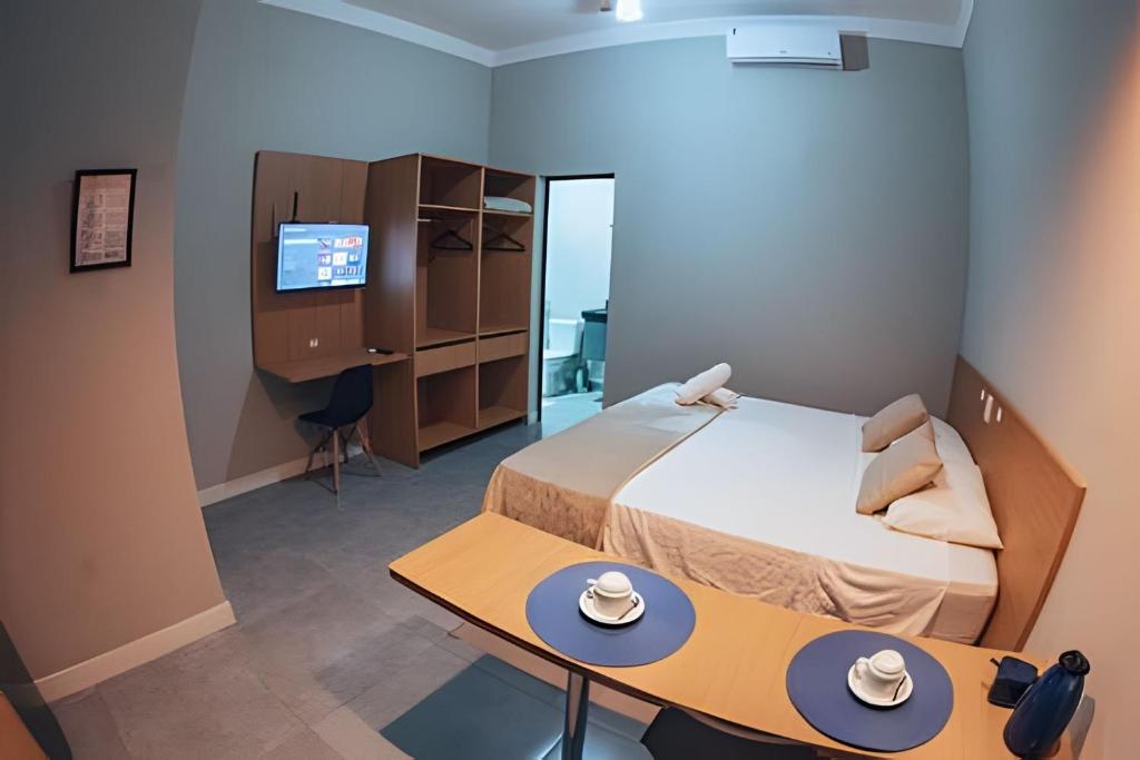 a room with a bed and a table and a computer at Zuccaro Studio in Bauru