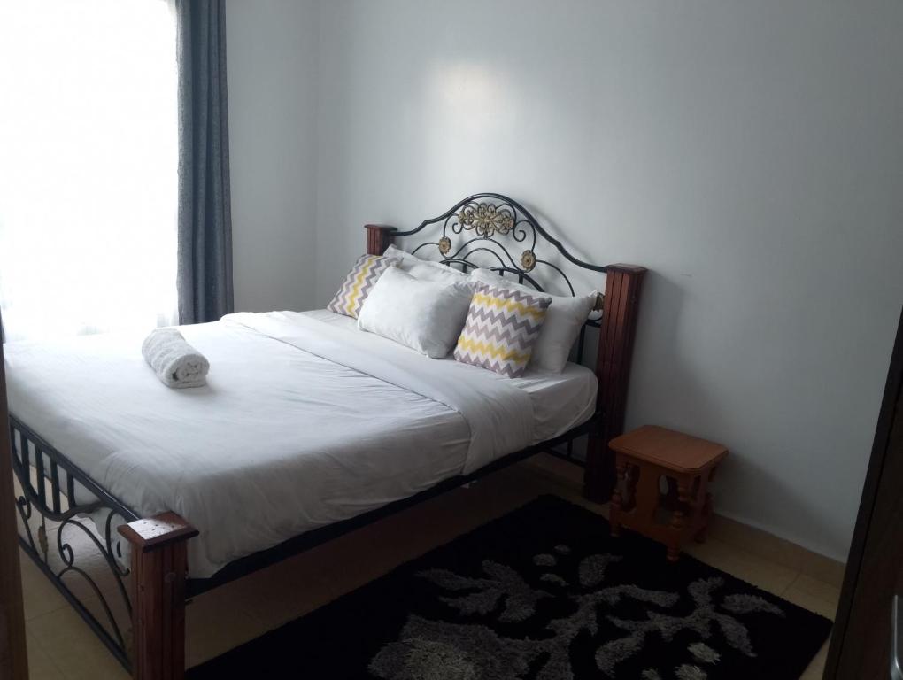 a bed with white sheets and pillows in a room at Unity Homes Eldoret in Eldoret